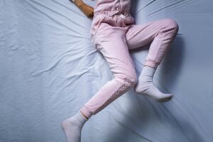 woman with restless legs syndrome moving legs while lying in bed